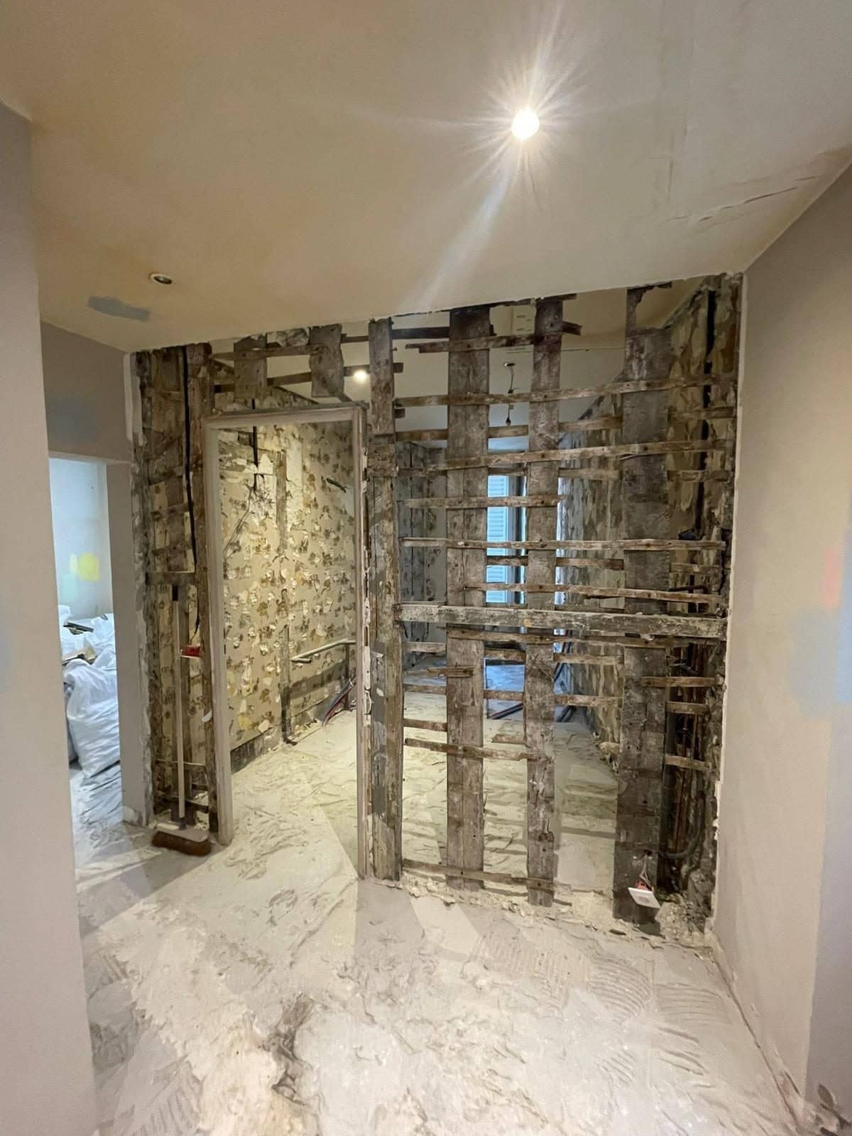 Cloison en pan de bois mise à nu pendant un chantier dans un appartement ancien : poteaux, lattis et plâtre visibles