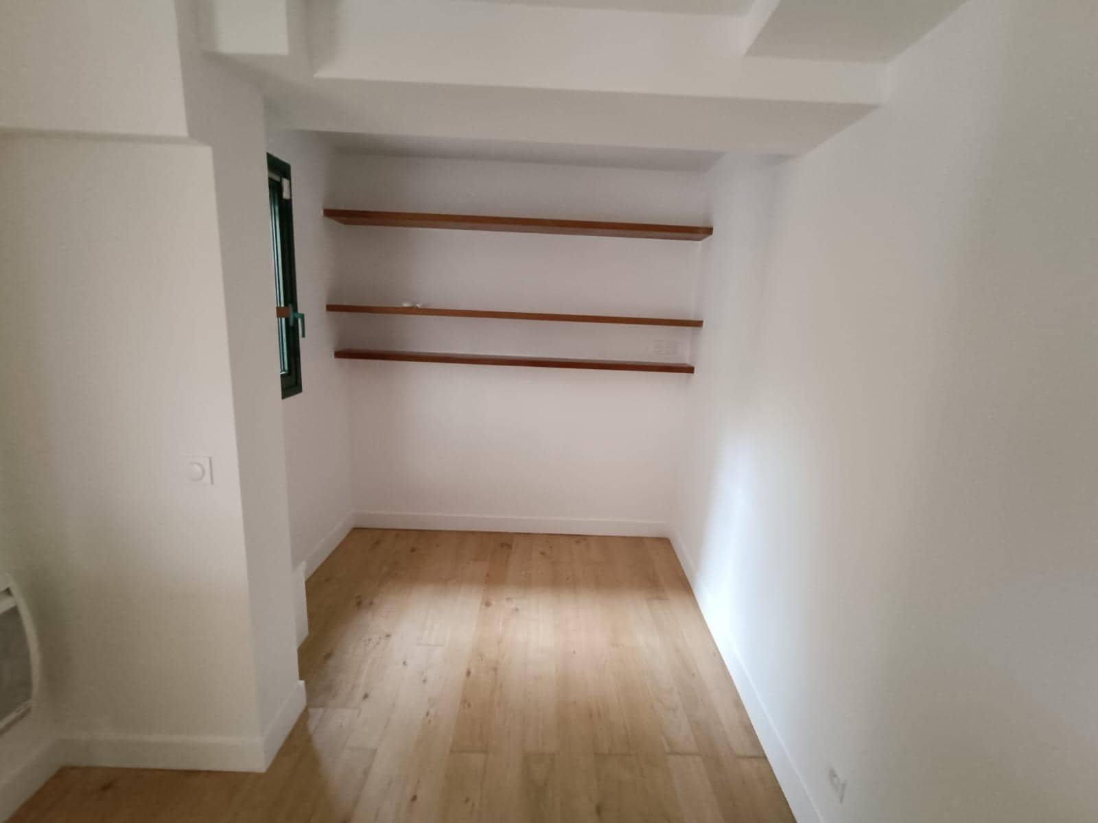 Pièce rénovée au parquet de chêne clair, étagères murales en bois et murs blancs