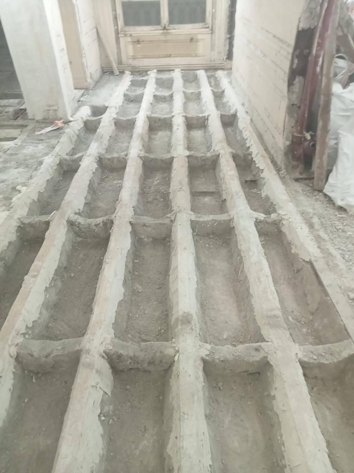 Plancher ancien mis à nu en cours de travaux : solives en bois parallèles et augets de remplissage