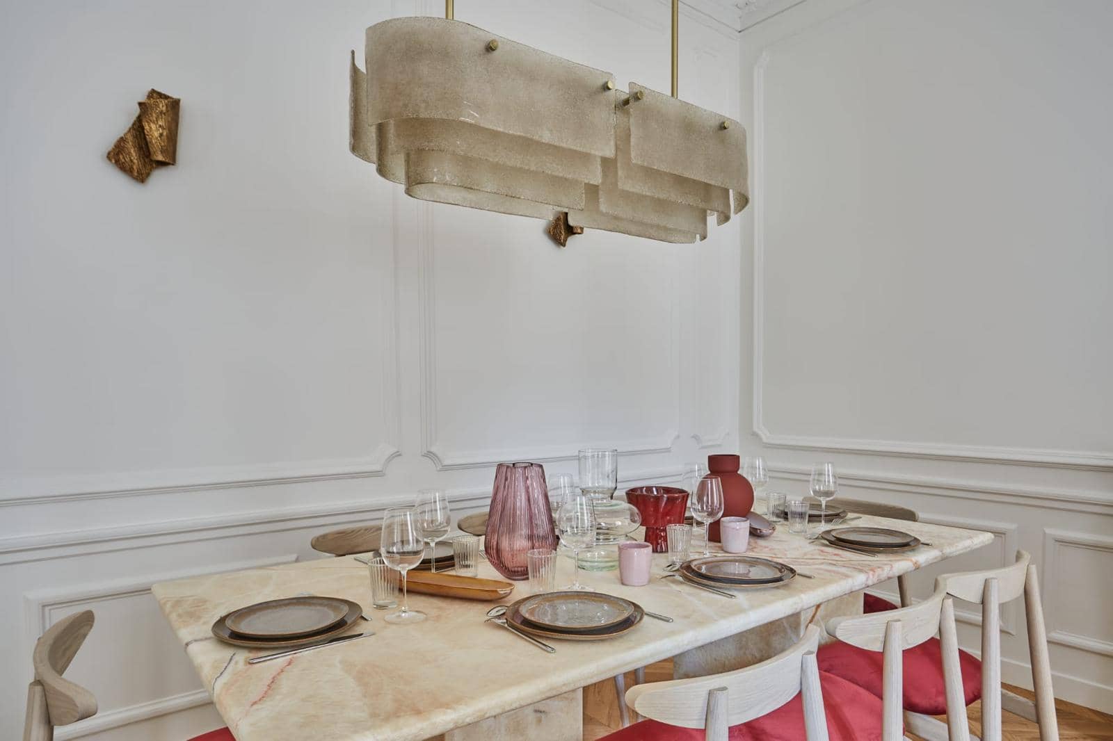 Salle à manger d'un appartement ancien : lambris moulurés, table en onyx et grande suspension en albâtre