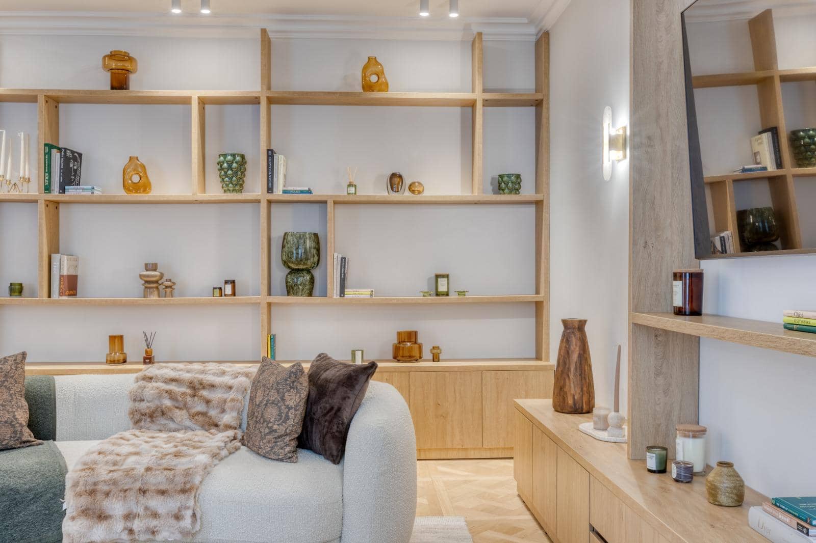 Salon rénové avec bibliothèque en chêne sur mesure, étagères éclairées et canapé