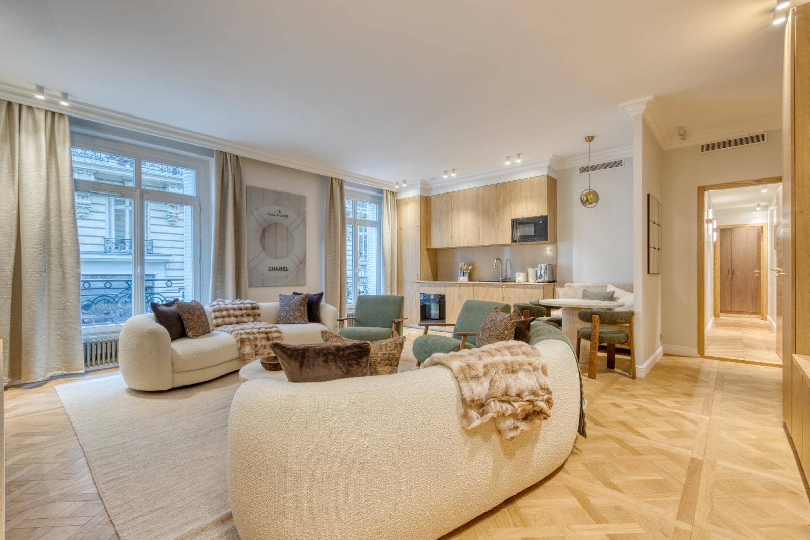 Appartement ancien restructuré : séjour ouvert sur la cuisine, canapé courbe, parquet en panneaux de Versailles